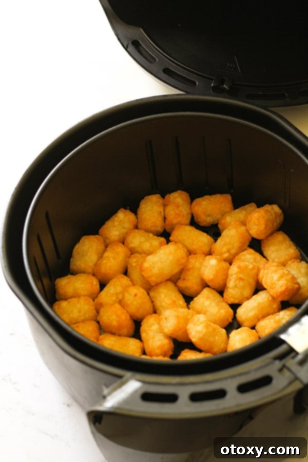 The same air fryer basket, now filled with exquisitely crispy and golden-brown tater tots, showcasing their perfect texture after cooking.