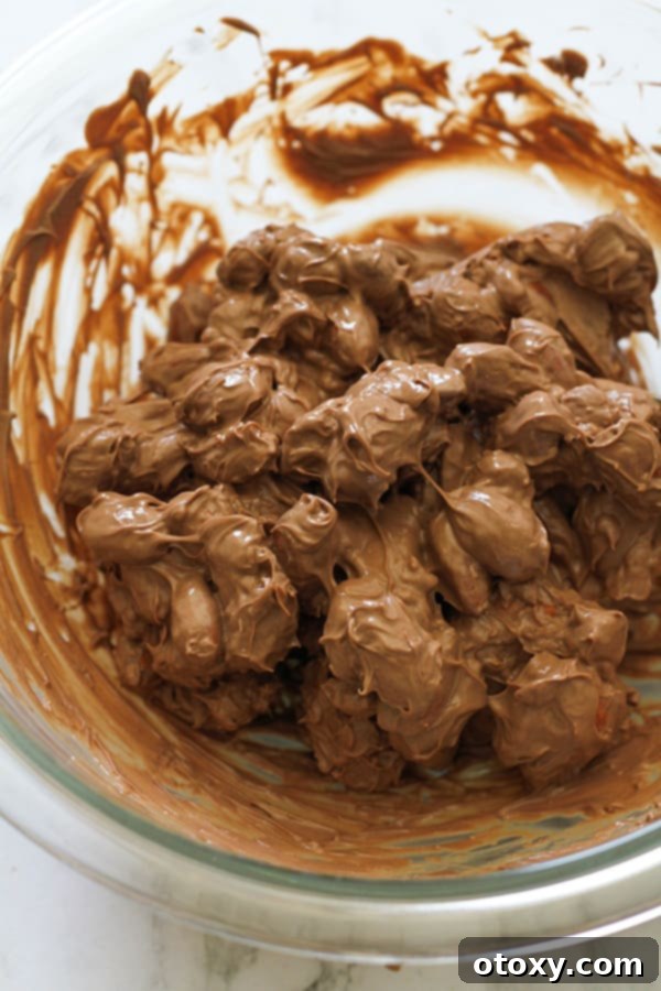 almonds covered in melted chocolate in a glass bowl.