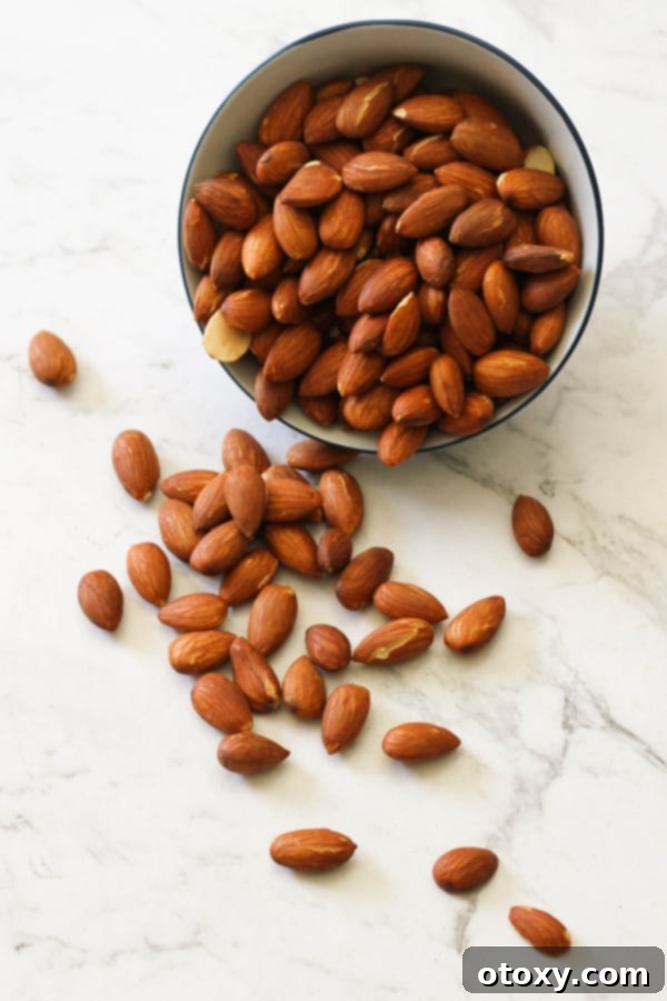 A small bowl brimming with perfectly dry roasted almonds, placed on a elegant white marble surface, highlighting their golden-brown color and inviting texture.