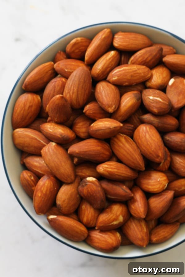 A close-up shot of dry roasted almonds arranged neatly in a small, rustic bowl, showcasing their even golden-brown color and inviting texture.