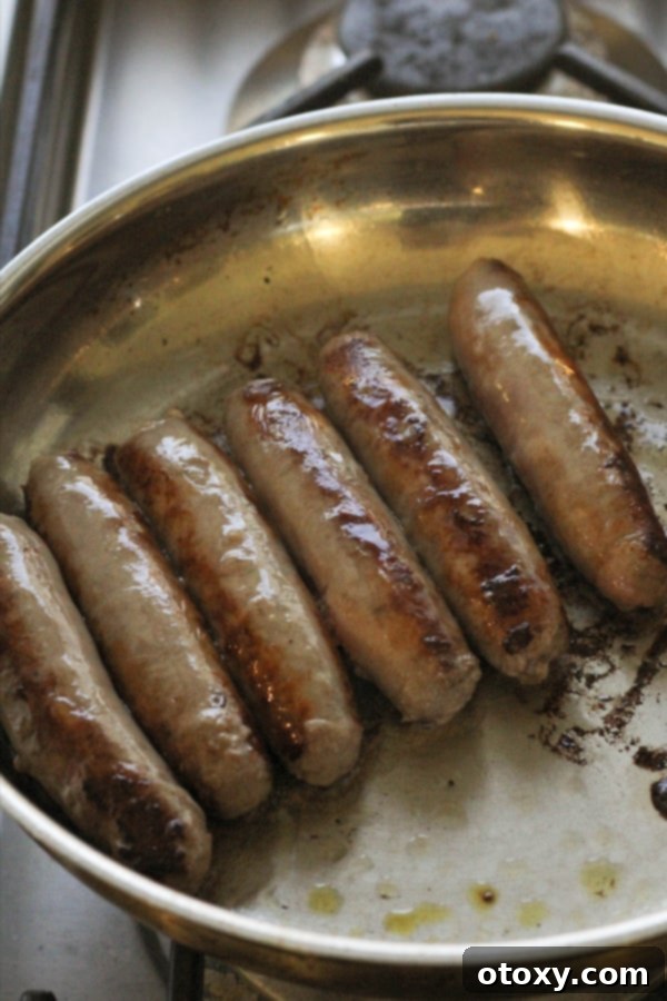 sausages sizzling and browning in a frying pan, indicating the start of a delicious meal.