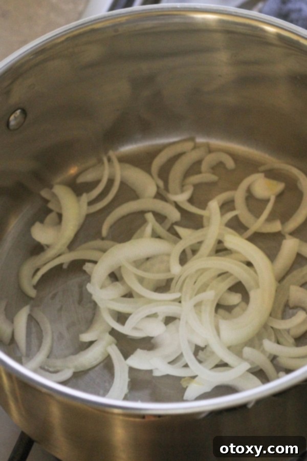 sliced onions gently cooking in a large pot, forming the aromatic base for the curry.