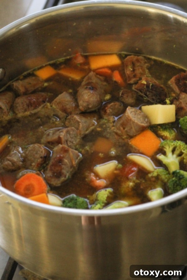 various ingredients for curried sausages, including vegetables and chopped sausages, simmering in a large pot, creating a rich stew.