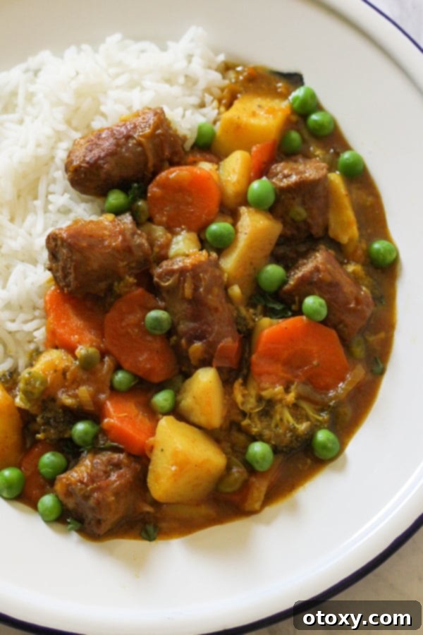 another close-up shot of curried sausages served on rice, highlighting the rich sauce and tender ingredients.