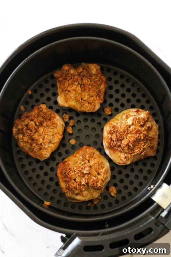 Perfectly cooked baked apples with golden-brown, crispy oat topping, still warm in the air fryer basket.