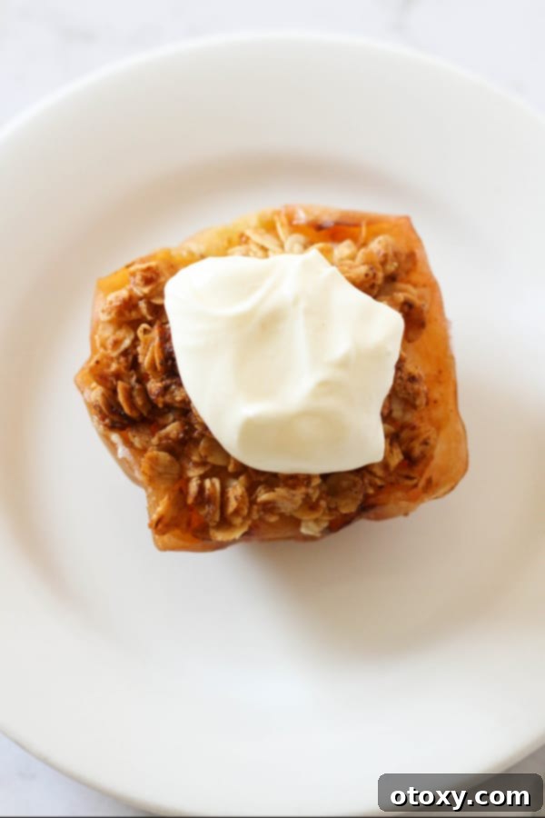 Delightful baked apple, crowned with a scoop of melting vanilla ice cream, presented on a pristine white plate.