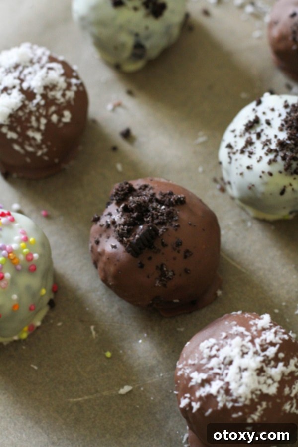Creamy Oreo Cheesecake Truffles 11 oreo balls laying on baking tray covered in cookie crumbs and sprinkles.