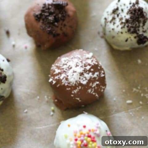 Creamy Oreo Cheesecake Truffles 12 oreo balls laying on baking tray covered in cookie crumbs and sprinkles.