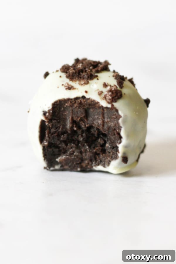 Creamy Oreo Cheesecake Truffles 3 oreo truffle with bite removed on a white marble background.