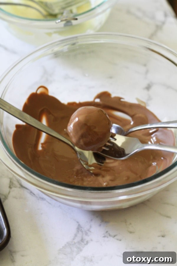 Creamy Oreo Cheesecake Truffles 8 a bowl of melted chocolate with a oreo ball sitting in it.