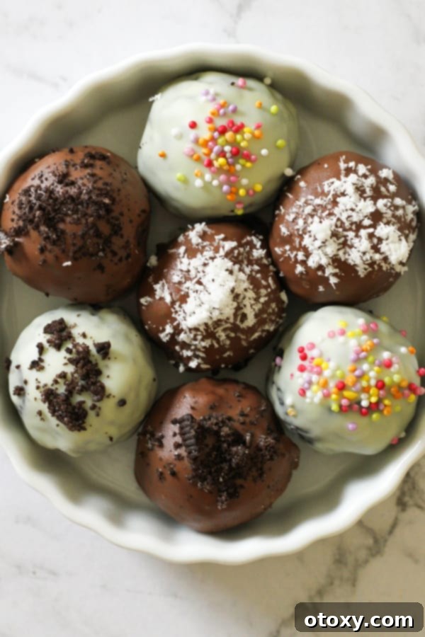 Creamy Oreo Cheesecake Truffles 10 oreo balls laying on baking tray covered in cookie crumbs and sprinkles.