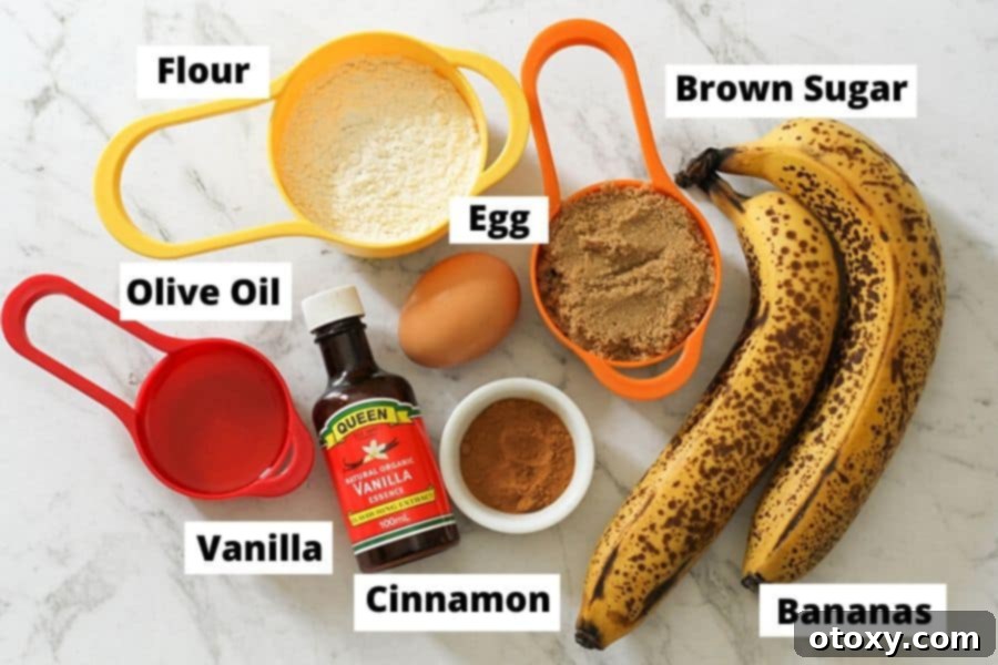 A flat lay photograph displaying all the ingredients for Air Fryer Banana Muffins neatly arranged on a white marble background.
