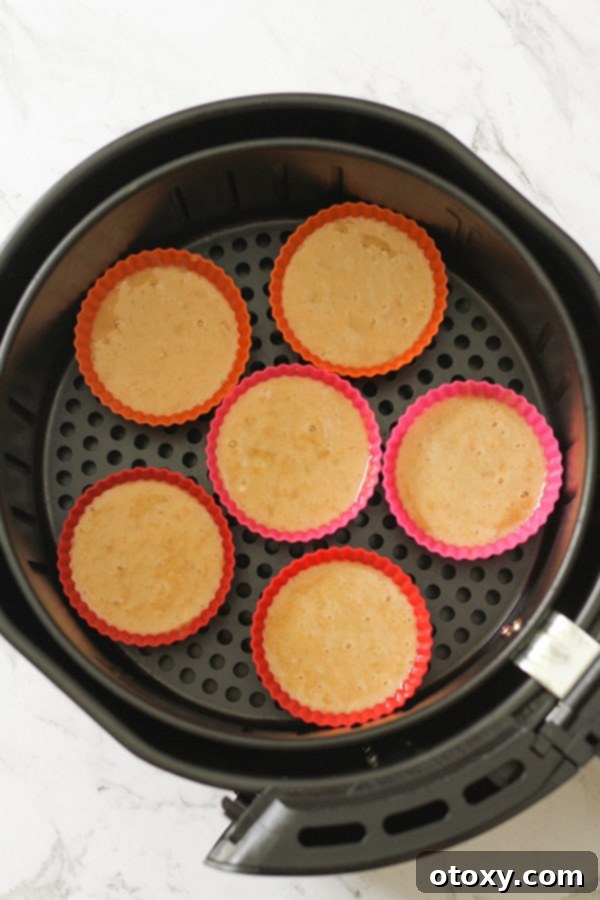 Muffin batter neatly poured into silicone muffin cases, ready to be placed inside the air fryer basket for baking.
