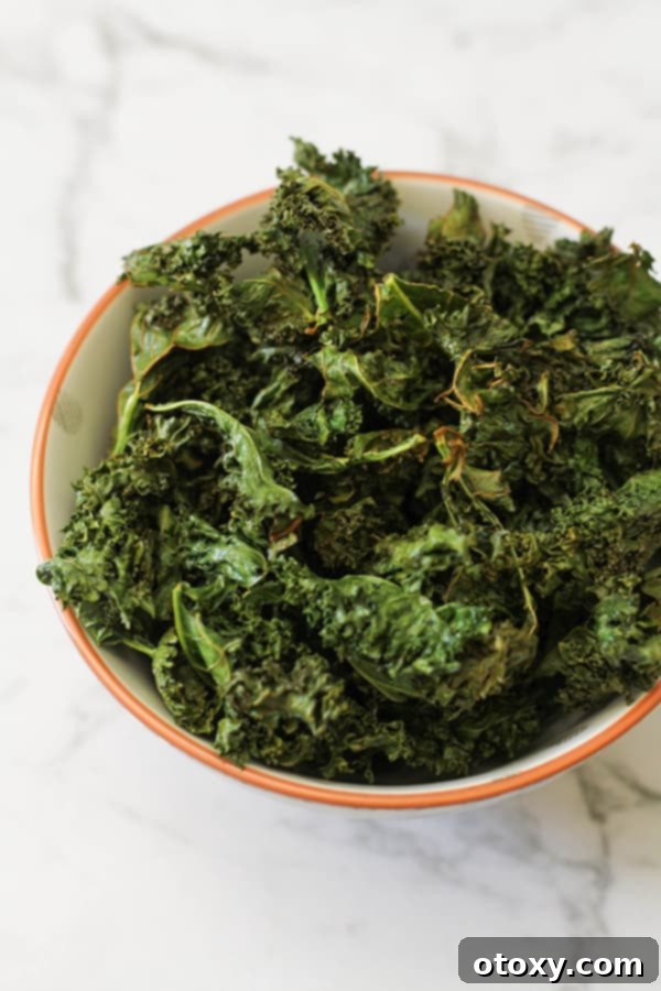 Sweet and Salty Air Fryer Kale Crisps 9 A generous serving of sweet and salty kale chips overflowing from a pristine white bowl, showcasing their crispy texture.