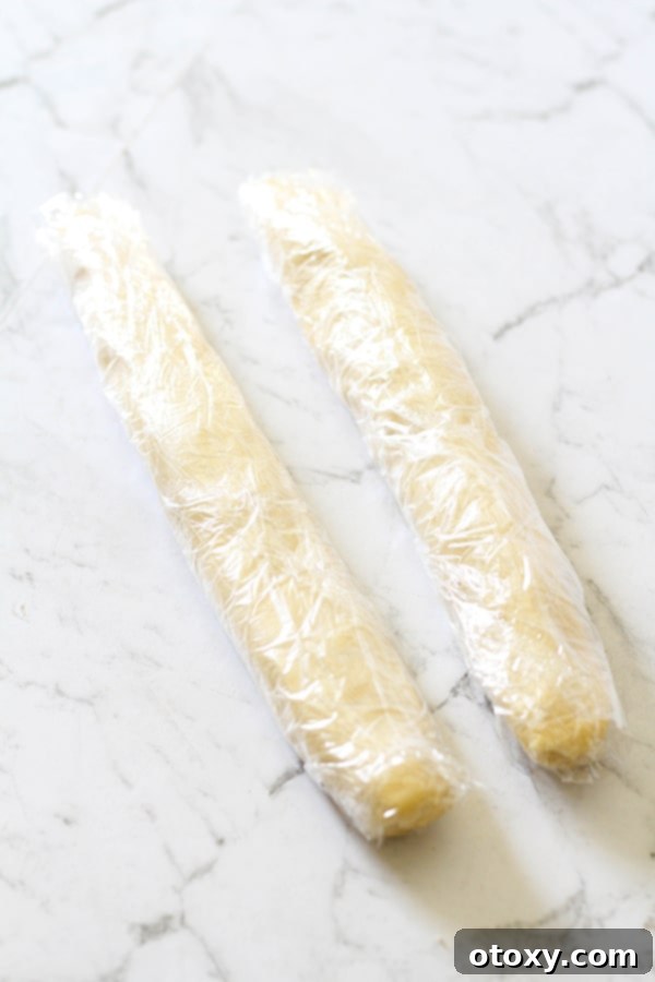 Two shortbread dough logs wrapped in plastic wrap, ready for chilling.