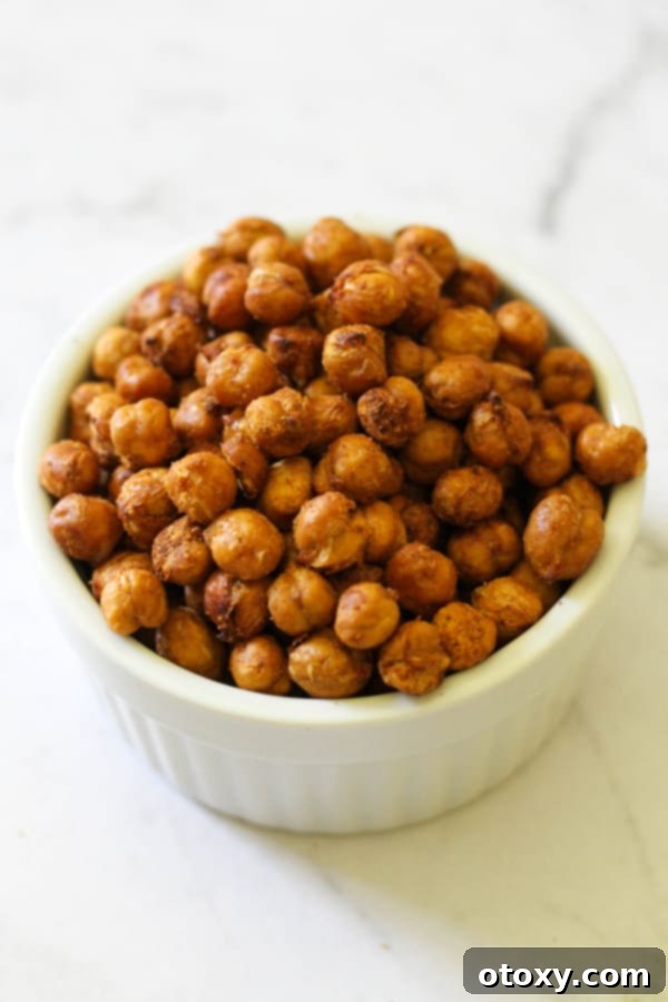 A white bowl filled with perfectly crispy, seasoned air-fried chickpeas, ready for snacking or topping meals.