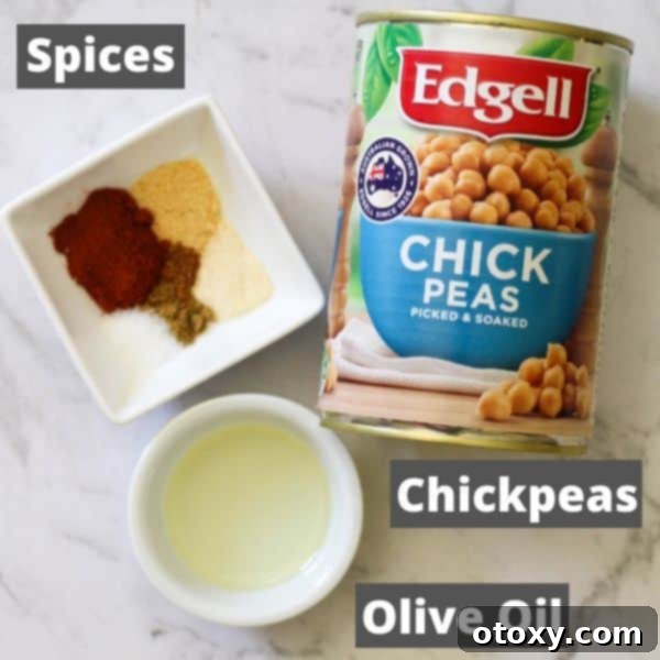 Arrangement of ingredients for crispy air fryer chickpeas including a can of chickpeas, olive oil, and various spices.