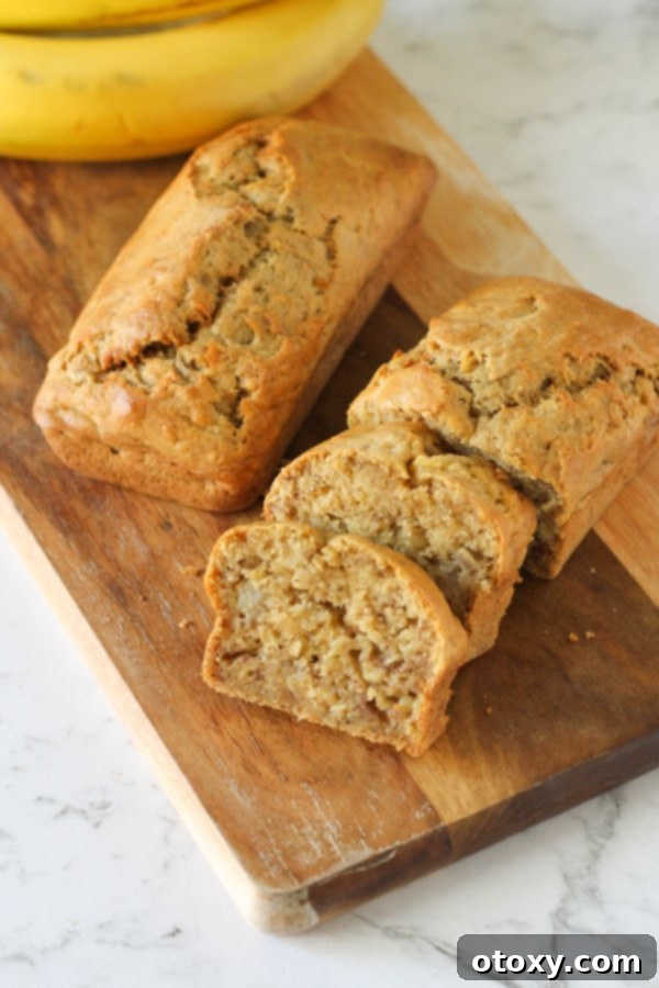 Two perfectly golden mini banana loaves on a rustic wooden cutting board, ready to be sliced and enjoyed.