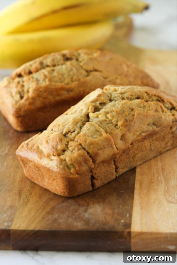 A pair of beautifully baked mini banana loaves sitting on a wooden cutting board, garnished slightly and ready for serving.