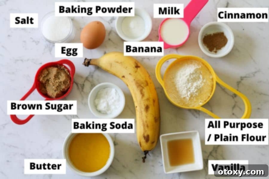 A selection of fresh ingredients for mini banana bread, including very ripe bananas, flour, sugar, and butter, neatly arranged on a white marble board.
