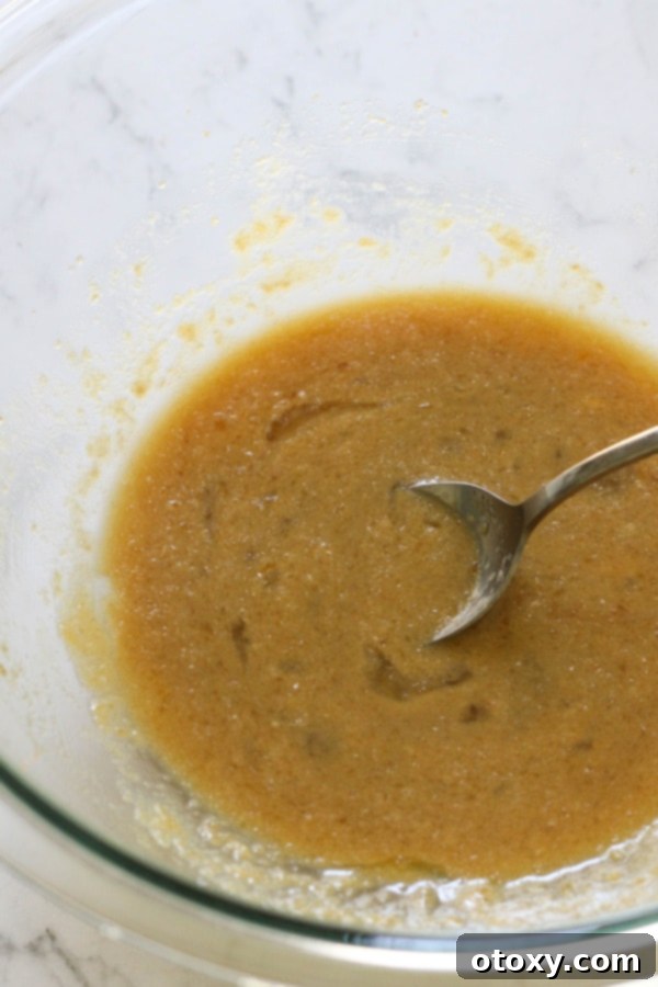 Melted butter and brown sugar mixed together in a clear glass mixing bowl, forming a creamy, rich base for the banana bread batter.
