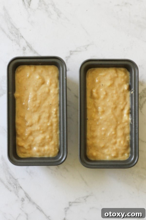 Two mini banana bread loaves filled with batter, nestled in their pans and perfectly ready for the air fryer.
