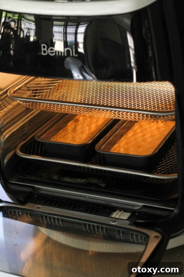 Mini banana loaves baking inside an air fryer, with a golden crust beginning to form.