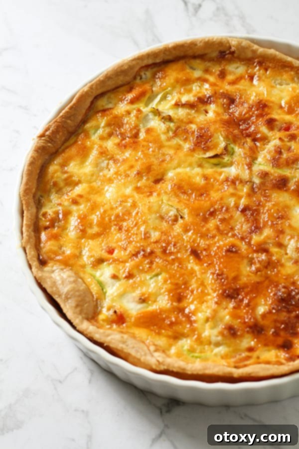 Fresh Garden Quiche 3 A close-up shot of a vegetarian quiche in a white ceramic dish, showcasing its golden crust and vibrant filling.