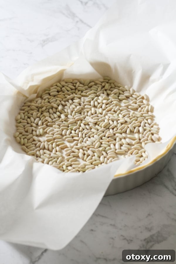 Fresh Garden Quiche 7 A quiche crust covered in baking paper and filled with pie weights, ready for the oven.