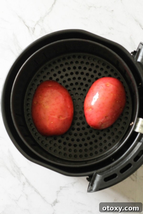 Air Fryer Potato Perfection 4 potatoes in an air fryer basket.