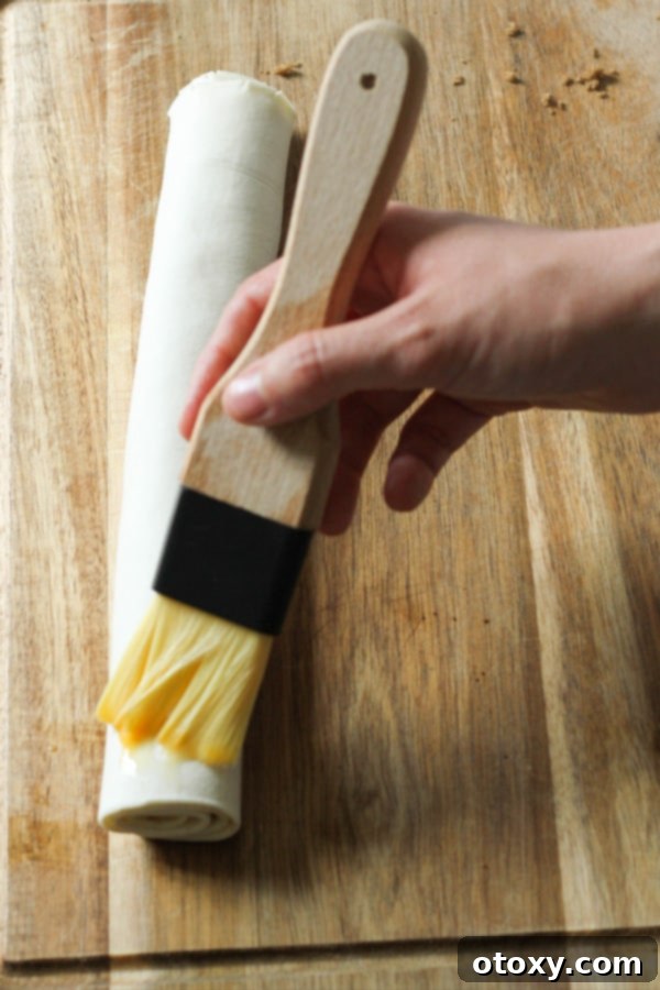 rolled pastry being brushed with eggs.