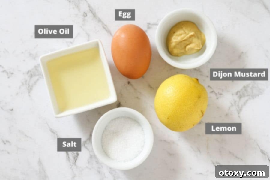 Fresh ingredients for Whole30 mayonnaise, including egg, olive oil, lemon, and dijon mustard, laid out on a white marble background.