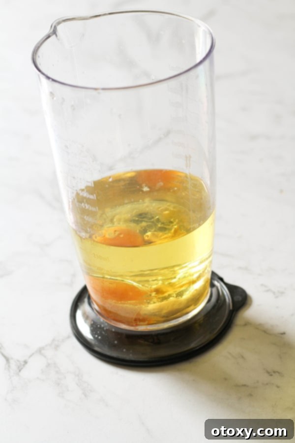 Ingredients for Whole30 mayonnaise carefully layered in a jar with the egg yolk at the bottom.