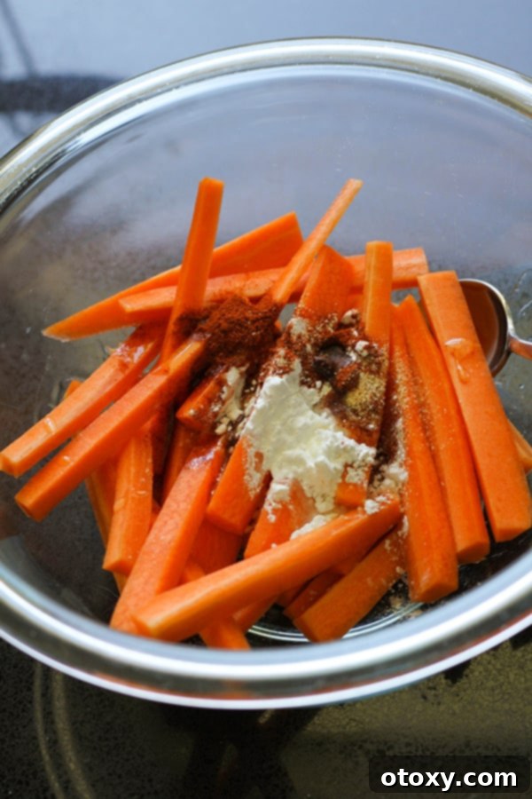 Carrot fries coated in spices and oil in a glass bowl.