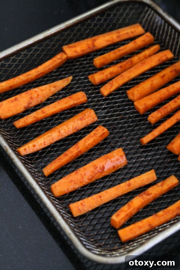 Air fryer basket filled with seasoned carrot fries arranged in a single layer.