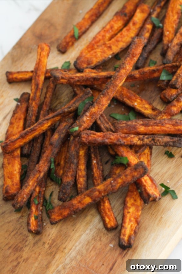 Air fryer carrot fries served on a wooden board with dipping sauce.