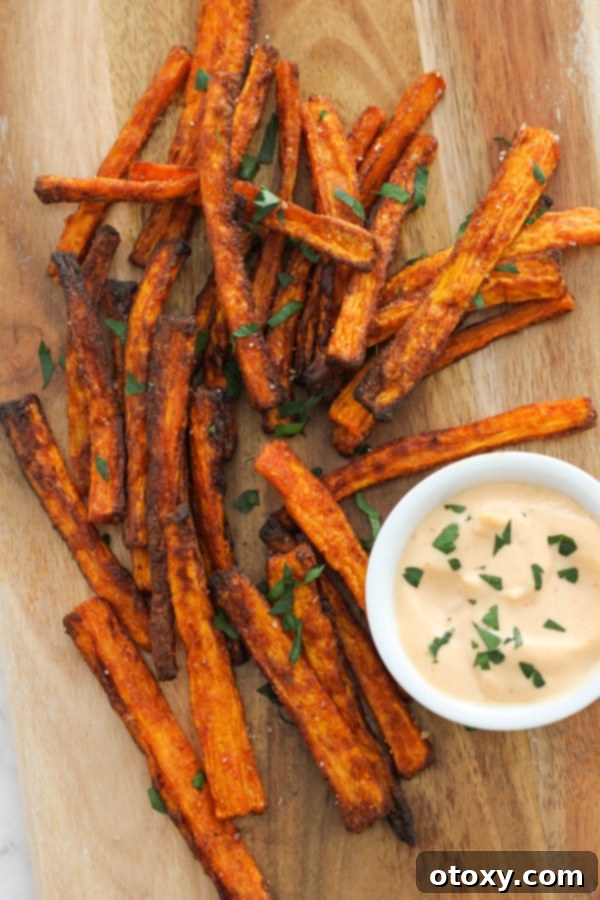 A close-up of a serving of air fryer carrot fries on a wooden board, showcasing their appealing texture.