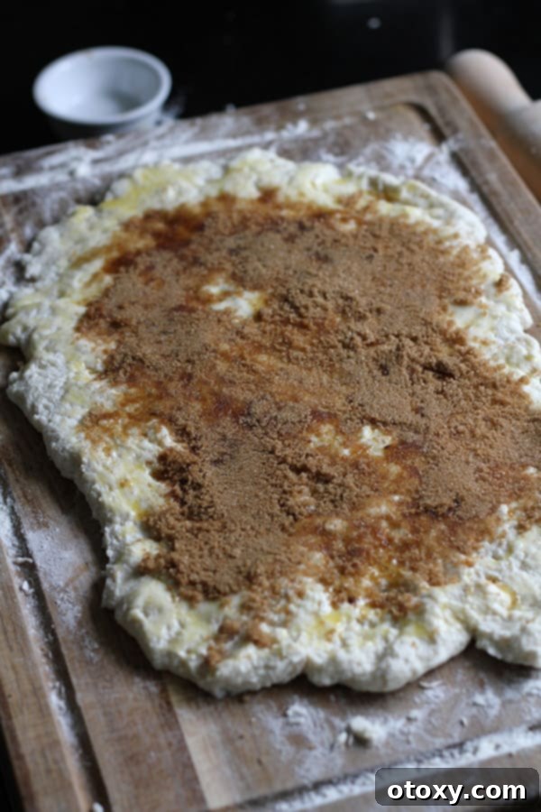 Air Fryer No Rise Apple Cinnamon Rolls 7 The rolled-out two-ingredient dough generously covered with melted butter, brown sugar, and cinnamon, preparing for the apple pieces.