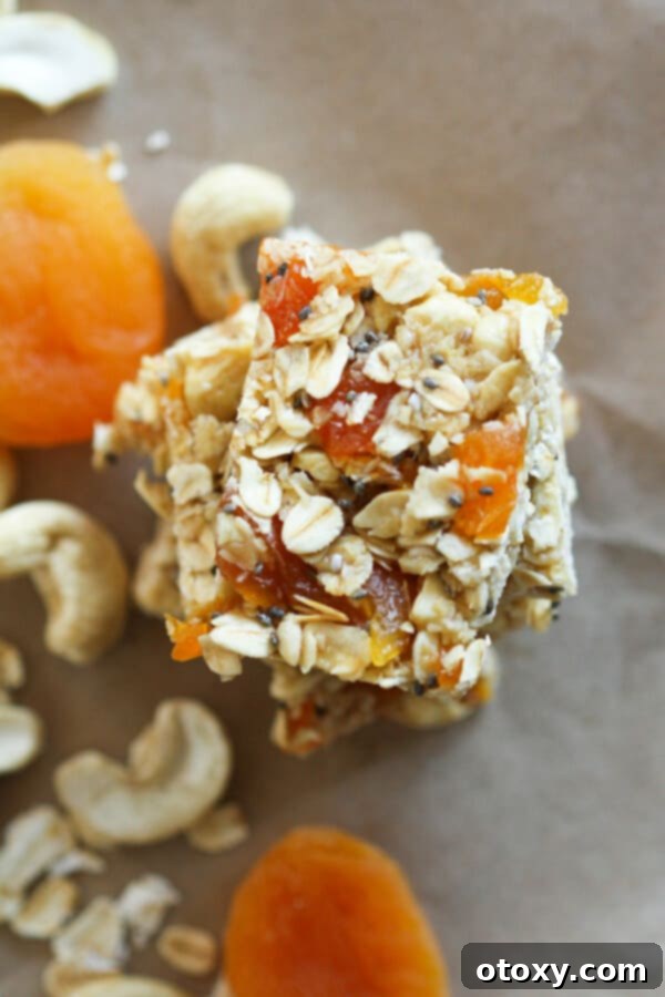 Effortless Chewy Apricot Granola Bars 2 chewy apricot muesli bars stacked on top of each other with cashews and apricots scattered around