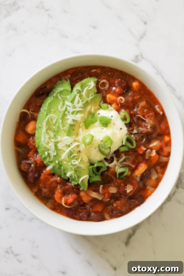 Triple Bean Vegetarian Chili 10 vegetarian three bean chili in a white bowl topped with greek yoghurt, avocado and spring onions.