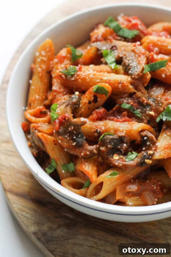 A beautifully plated bowl of creamy Tomato Mushroom Pasta, garnished with fresh basil leaves, ready to be enjoyed.
