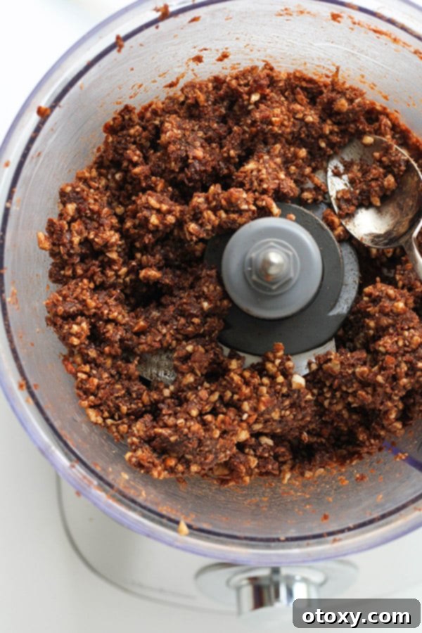 processed chocolate coconut energy ball mixture in a food processor, showing a cohesive dough texture.