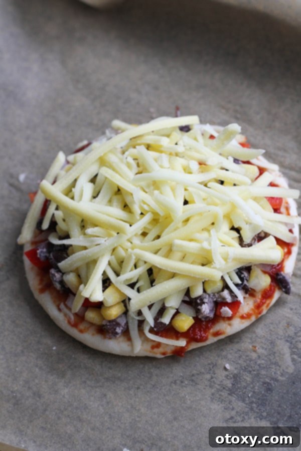pizza base covered in cheese on a baking tray.