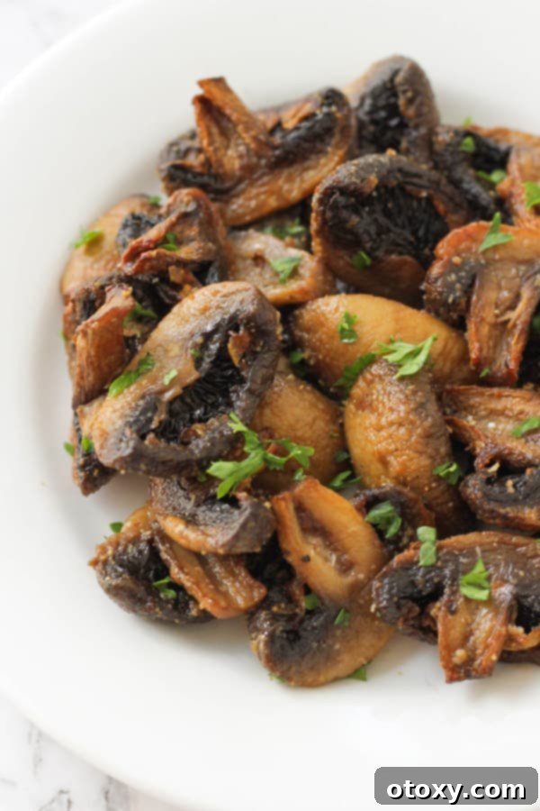 Crispy Air Fried Mushrooms 2 Crispy air fryer mushrooms on a white plate, ready to serve.
