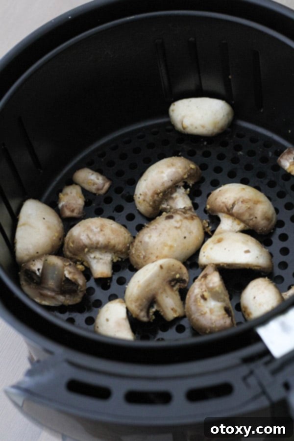 Crispy Air Fried Mushrooms 6 Seasoned mushrooms in a single layer within an air fryer basket.