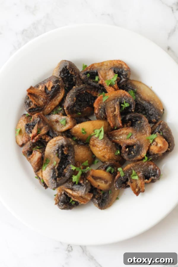 Crispy Air Fried Mushrooms 9 Delicious air fryer mushrooms garnished with fresh parsley on a white plate.