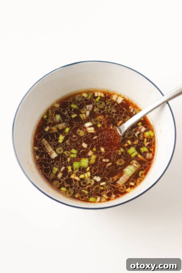 A close-up shot of a small bowl containing the mixed sriracha sauce ingredients, ready to be added to the pan.