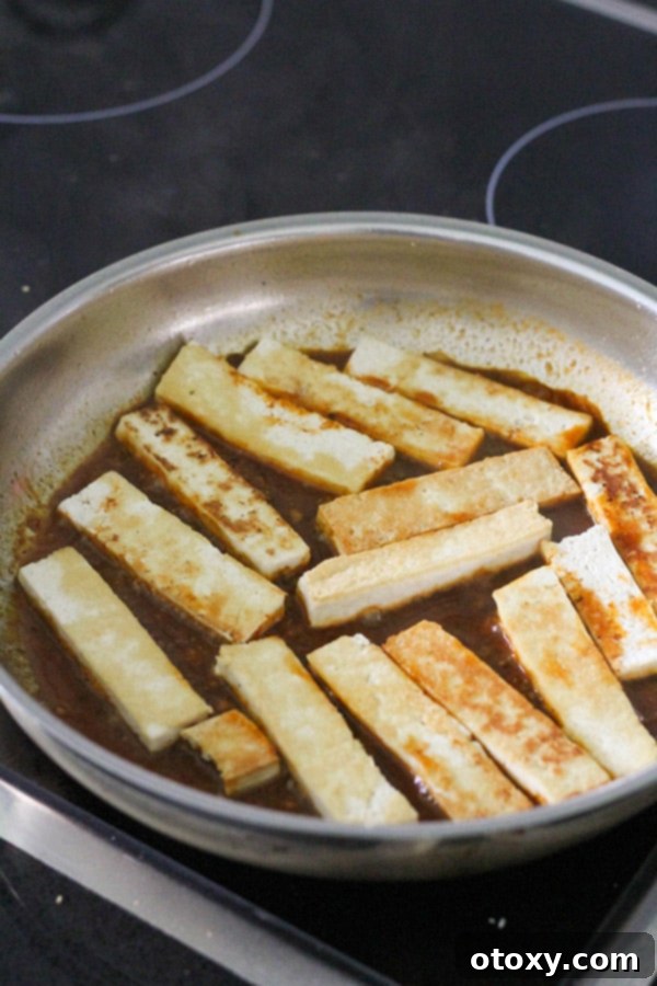 Pan-fried tofu pieces simmering in the reduced sriracha sauce, coating each piece beautifully.